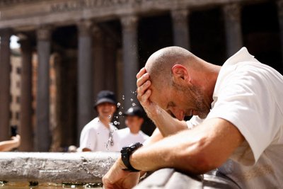 Turistas Romoje po ilgo laukimo eilėje bando atsigaivinti prie fontano 