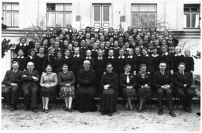 Kretingos pranciškonų gimnazijos mergaitės su pedagogais prie Šv. Antano rūmų pradedant mokslo metus 1939 m. Iš kairės: poetas Antanas Kirtiklis, Juozas Gedgaudas, centre kairėje Kretingos pranciškonų gimnazijos direktorius V.Zajančkauskas, dešinėje Kretingos Šv.Antano kolegijos rektorius tevas Justinas Vaškys, pirmas iš dešinės dailininkas darbėniškis Fabijonas Šulcas, antras iš dešinės Antanas Masionis.