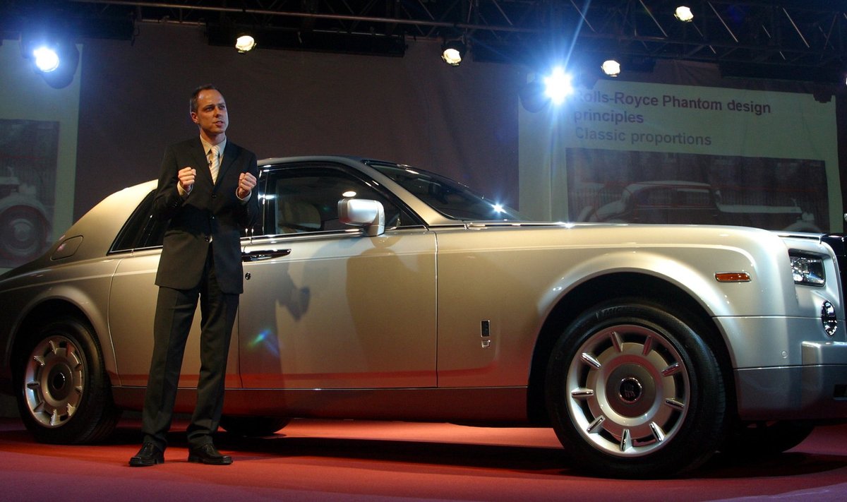 Ianas Cameronas pozuoja prie "Rolls-Royce" markės automobilio