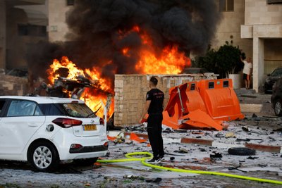 A man stands on a road as fire burns after rockets were launched from the Gaza Strip, in Ashkelon, Israel October 7, 2023. REUTERS/Amir Cohen