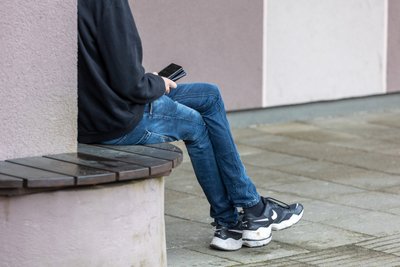 Paauglys naudojasi mobiliuoju telefonu.
