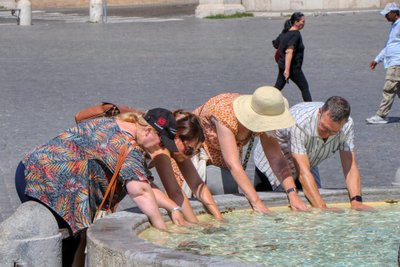 Turistai vėsinasi fontanų vandeniu