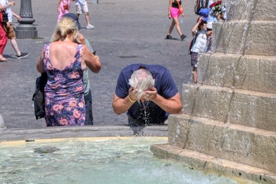 Turistai vėsinasi fontanų vandeniu